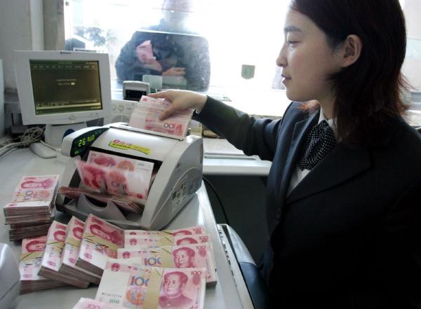 银行员工正在用点钞机点验百元人民币现钞