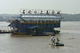 图为7月19日湘江水上排档正依靠危险性极高的"油桶筏"接送食客.