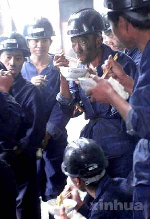 7月16日,一群抢险队员从井下上来后在矿井边吃饭.新华社记者赵鹏摄