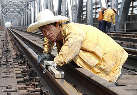 图文:南昌一铁路工人在铁轨上加紧测量作业