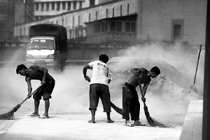 嘉滨路二码头附近的公路边,3名工人正在清扫残留的石沙,灰尘漫天飞舞