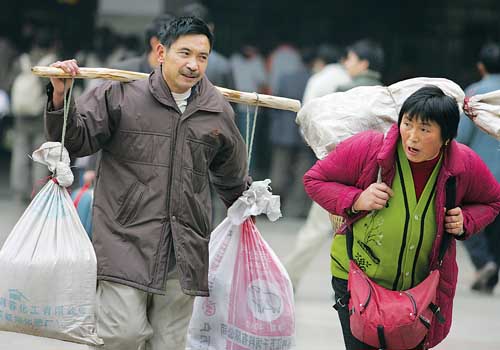 昨日,菜园坝汽车站,两位民工肩挑背扛地匆匆赶路回家 记者 唐明 摄