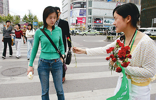 5月8日,在上海杨浦区街头,手捧鲜花的志愿者向一名遵守交通规则的