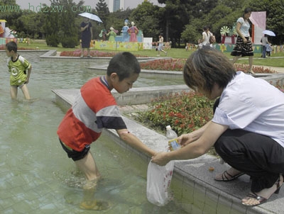 孩子公园水池捞鱼母亲在旁助阵