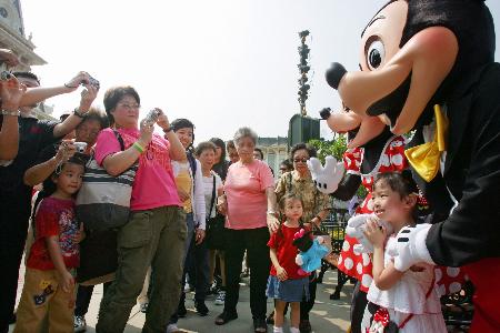 图文：游客在迪斯尼乐园与米老鼠拍照合影