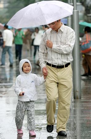 图文:一对父女在雨中打伞走在杭州街头