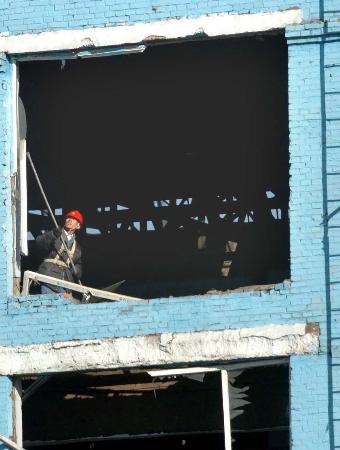 图文：一名工人在被破坏的厂房内清理现场
