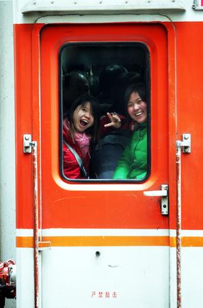 图文:女孩儿在拥挤的火车过道内向窗外挥手