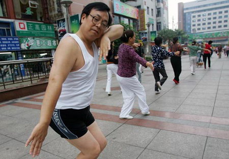 图文:爱锻炼的中年男子跟妇女们跳起健身舞蹈