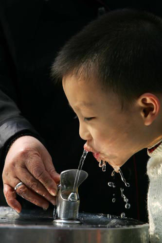 图文:小孩在自动饮水机前喝着清凉的自来水