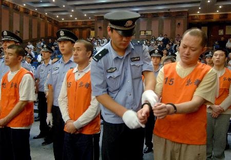 34名涉案犯被判刑       8月11日,法警在给胡亚东(前排右一)戴上手铐
