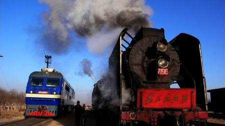 2006年12月27日,宁夏最后一台蒸汽火车qj7195旁驶过一辆内燃机车.