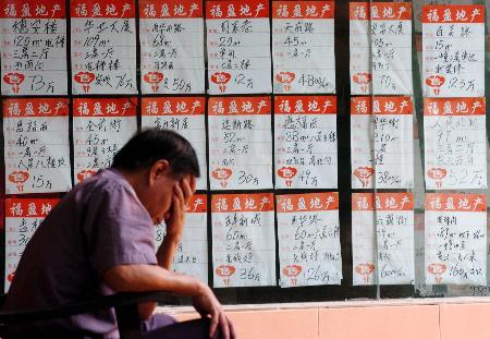 图文:广州市民坐在房地产中介公司的广告牌前