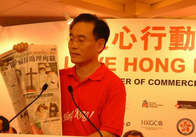 香港韩人商工会会长李勉官举起报纸,表示全力支持防治sars一线的医护