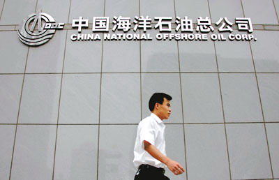 一名行人走过中海油总部大楼,压图曲线为中海油股价走势图(2005年1