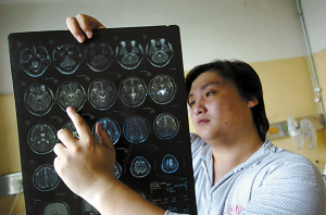 一位正在接受治疗的北京市民拿着自己的脑部ct图. 《新京报》供图
