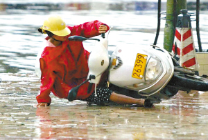 大雨天,一辆摩托车进入广场时连人带车摔倒在雨中. 记者龙成通 摄