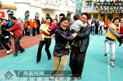 父母和孩子一起参加"抬轿子"亲子游戏比赛.黄旭胡摄