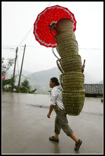 图文:一位农妇背着箩筐冒雨赶集