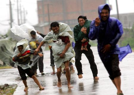 图文:村民携孩子顶着狂风暴雨艰难地赶路前行