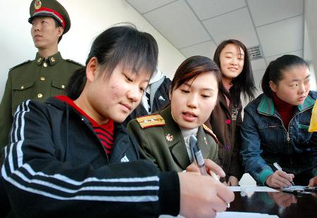 11月20日,一名女兵在银川警备区女兵报名点指导大学生填写报名表