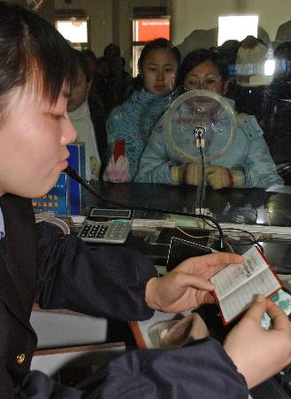 济南/济南火车站的售票工作人员在查看学生证