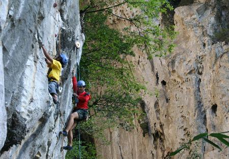 贵州格凸河穿洞风景区以奇美的喀斯特地貌闻名,运动员在攀岩