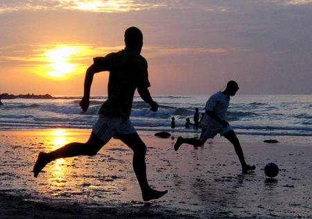 在落日海滩踢足球的塞内加尔年轻人