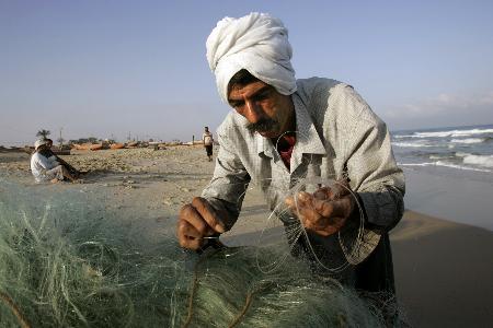 图文：一名巴勒斯坦渔夫在加沙海滩整理渔网