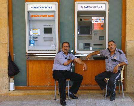 图文:银行保安坐在已停止运行的自动提款机前