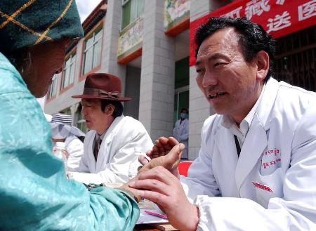 6月20日,西藏藏医学院教师顿珠(右)在为堆龙德庆县德庆乡农牧民看病