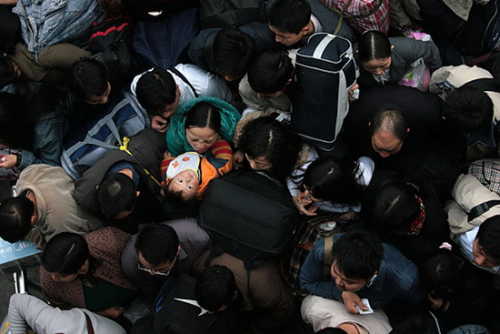 图文:妇女抱着孩子从拥挤的人群中等候进站上车