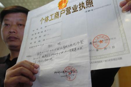 省贵定县政府法制办主任李明在展示一家假公司伪造的营业执照和证明