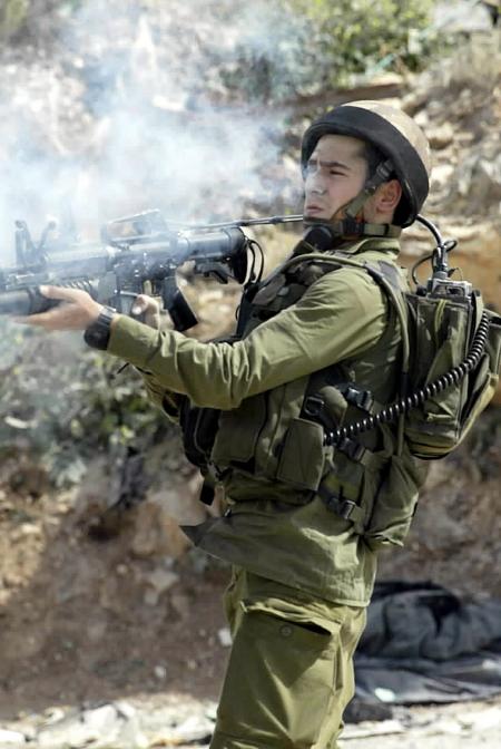 4月18日,一名以军士兵在卡兰迪亚检查站附近向巴勒斯坦青年发射催泪弹