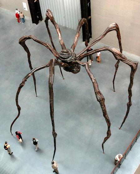 几名参观者在英国伦敦泰特现代艺术馆观看一个巨型蜘蛛雕塑