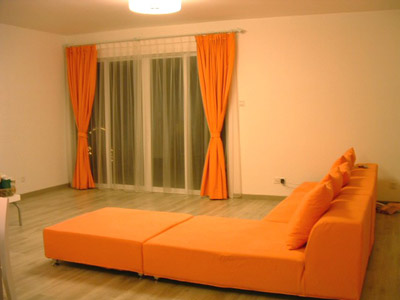 空旷的客厅,橙色的沙发和窗帘感觉很温暖