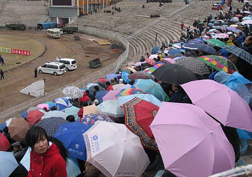 图文-延边球迷震撼中国赛场 球迷冒雨打伞坐看台